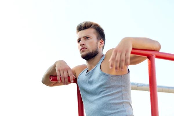 Young man exercising on parallel bars outdoors — Stock Photo, Image