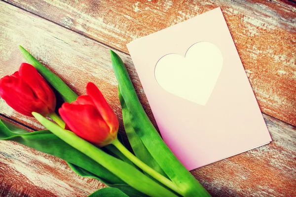 Close up of tulips and greeting card with heart — Stock Photo, Image