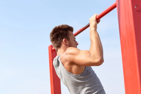 Joven ejercitándose en barra horizontal al aire libre —  Fotos de Stock