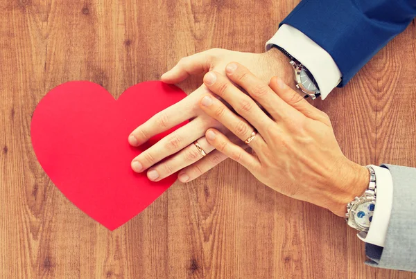 Close up of male gay couple hands with red heart — Stock Photo, Image