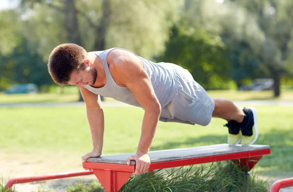 Joven haciendo ejercicio en el banco en el parque de verano —  Fotos de Stock