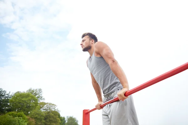 Jongeman die buiten op de horizontale balk traint — Stockfoto