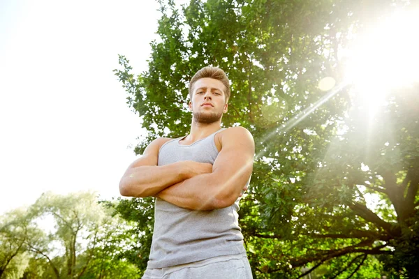Sporty young man with crossed arms at summer park — Stock Photo, Image