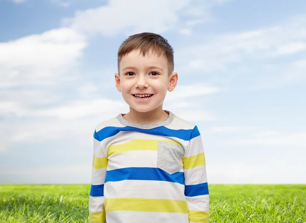 Niño sonriente sobre el cielo azul y el campo verde — Foto de Stock