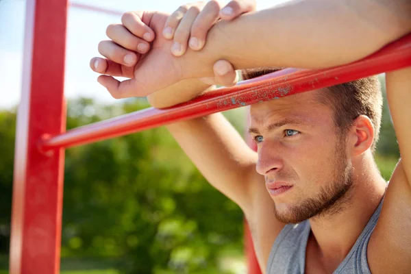 Junger Mann turnt im Freien am Reck — Stockfoto