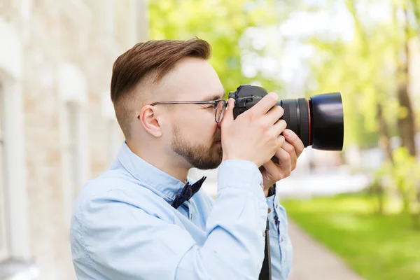 Jonge hipster man met digitale camera in stad — Stockfoto