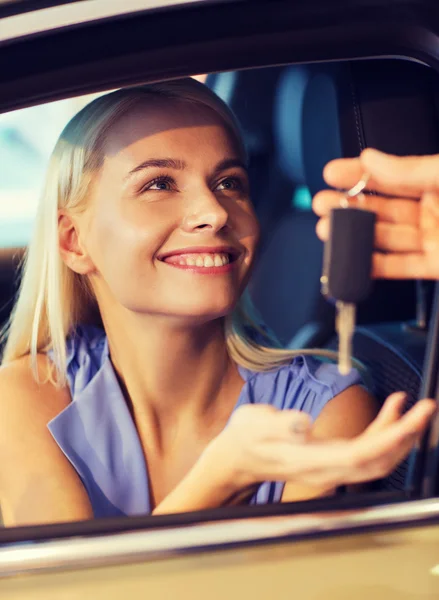 Mujer feliz consiguiendo la llave del coche en demostración auto o salón —  Fotos de Stock