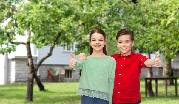 Щасливий хлопчик і дівчинка показують великі пальці на задньому дворі — стокове фото