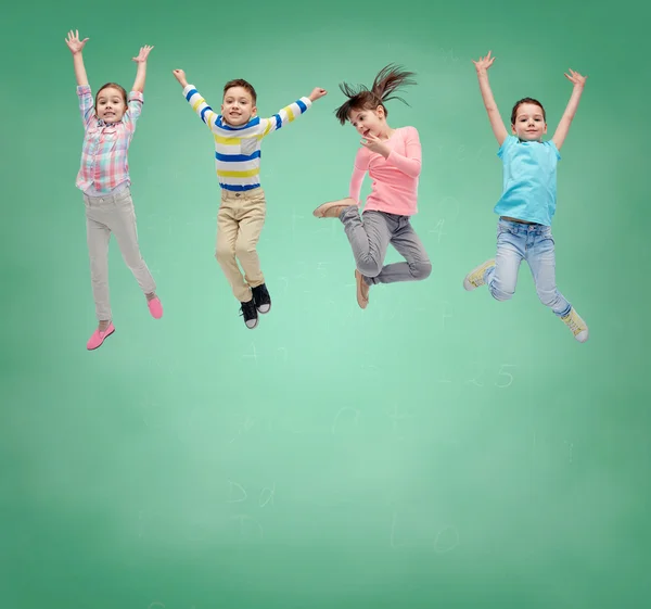 Happy little girl jumping in air over school board — Stock Photo, Image