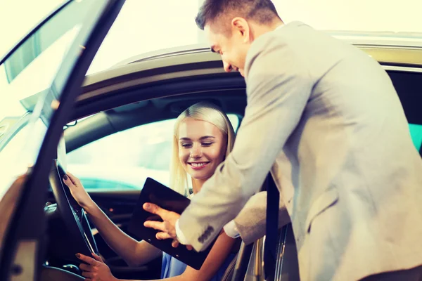 happy woman with car dealer in auto show or salon