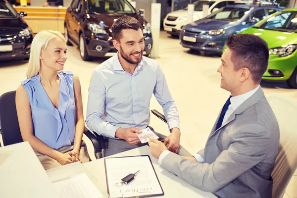 Feliz pareja con concesionario de coches en auto show o salón — Foto de Stock