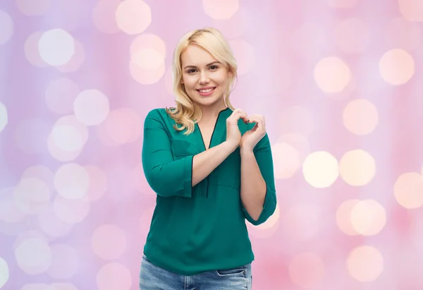 Smiling young woman in shirt showing heart shape — Stock Photo, Image