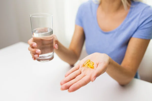 Close up of woman hands with capsules and water — Stock Photo, Image