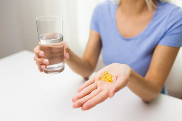 Gros plan des mains de la femme avec des capsules et de l'eau — Photo