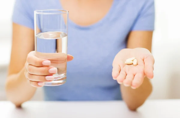 Primer plano de las manos de la mujer con pastillas y agua — Foto de Stock