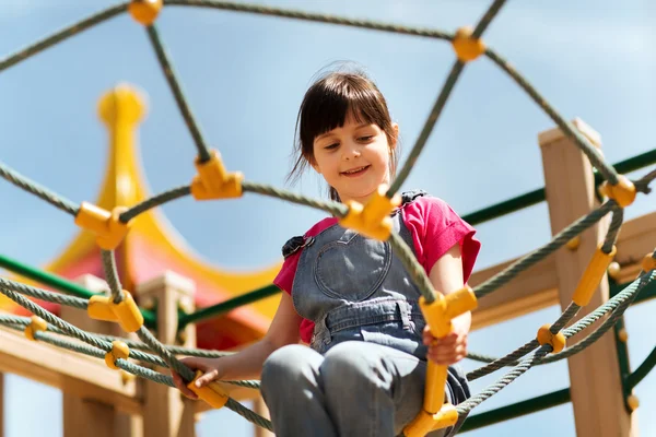 Fröhliches kleines Mädchen klettert auf Kinderspielplatz — Stockfoto