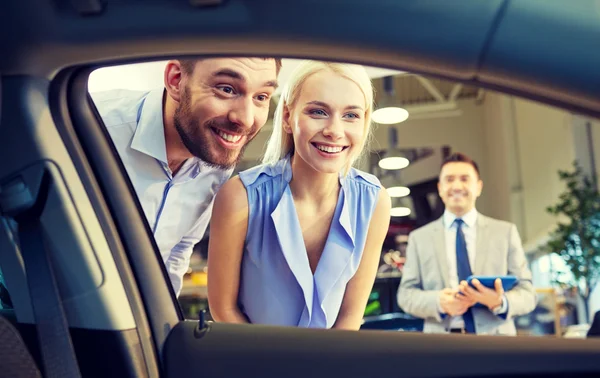 Casal feliz com revendedor de carro em auto show ou salão — Fotografia de Stock