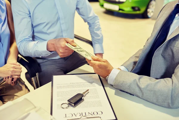 Clientes que dan dinero al distribuidor de coches en el salón de automóviles — Foto de Stock