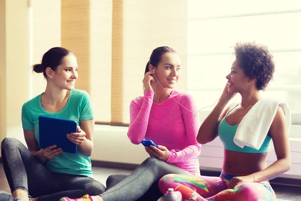 Gelukkig vrouwen luisteren naar muziek in de sportschool — Stockfoto