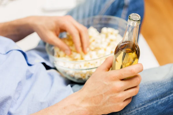 Close up de homem com pipocas e cerveja em casa — Fotografia de Stock