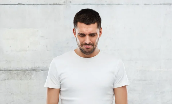 Unhappy young man over gray wall background — Stock Photo, Image