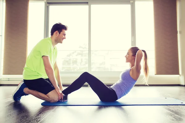 Donna con personal trainer che fa sit up in palestra — Foto Stock