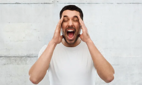 Galen skriker mannen i t-shirt över grå vägg — Stockfoto