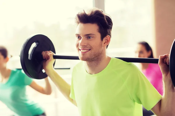 Grupo de personas haciendo ejercicio con barra de pesas en el gimnasio — Foto de Stock