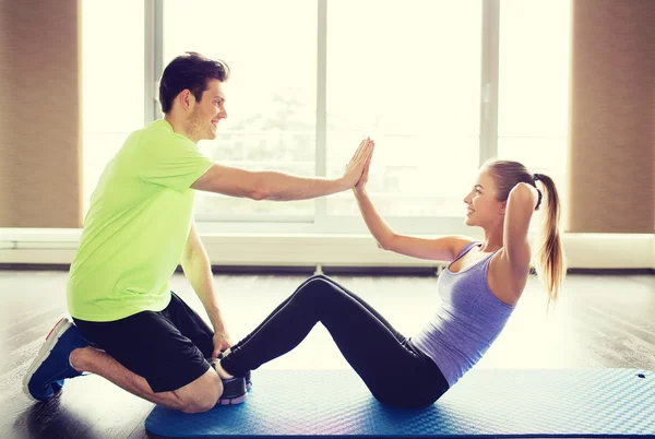 Vrouw met personal trainer doen sit ups in gym — Stockfoto