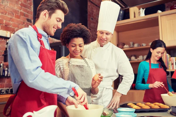 Happy friends and chef cook baking in kitchen — Stock Photo, Image