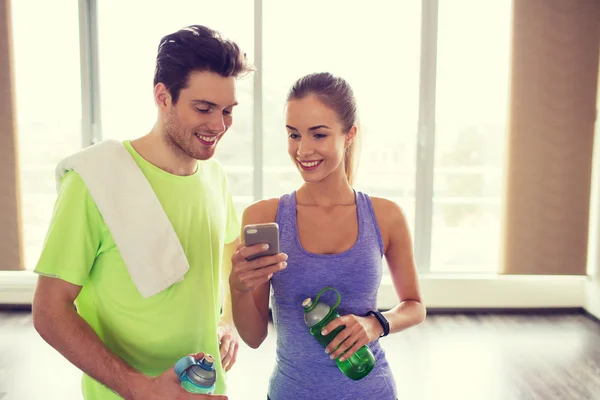 Donna felice e allenatore mostrando smartphone in palestra — Foto Stock