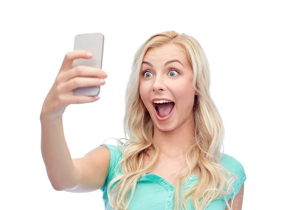Улыбающаяся молодая женщина делает селфи со смартфоном — стоковое фото