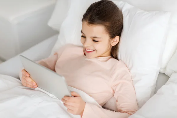 Happy girl lying in bed with tablet pc at home — Stock Photo, Image