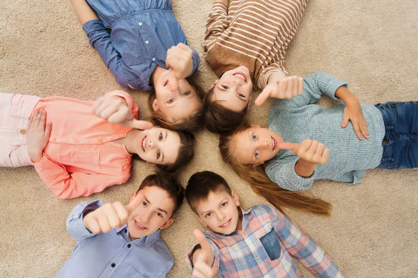 Enfants heureux montrant pouces sur le sol — Photo