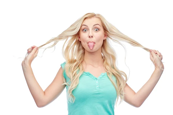 Happy young woman showing tongue and holding hair — Stock Photo, Image