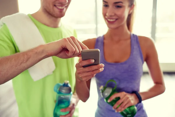 happy woman and trainer showing smartphone in gym