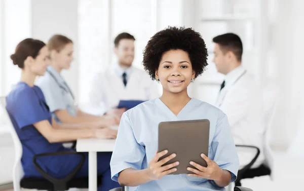 Médico feliz com tablet pc sobre a equipe na clínica — Fotografia de Stock