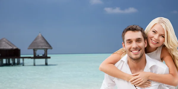 Happy couple having fun over beach with bungalow — Stock Photo, Image
