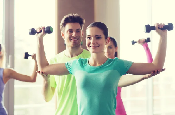 Glückliche Frauen und Trainer mit Kurzhanteln im Fitnessstudio — Stockfoto