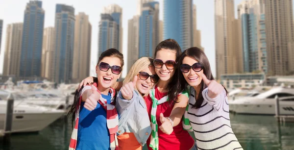 Young women showing thumbs up over city harbour — Stockfoto