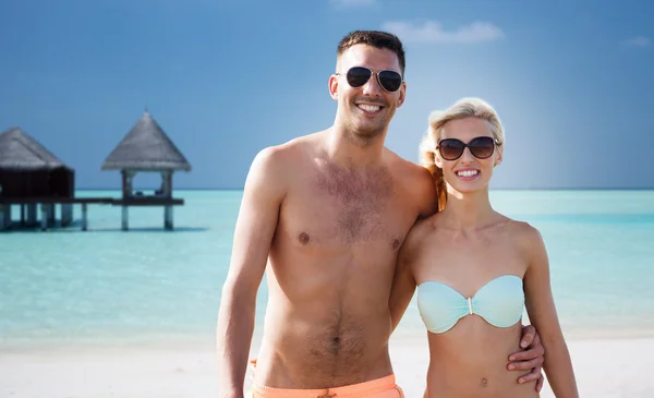 Счастливая пара в купальниках обнимается на летнем пляже — стоковое фото