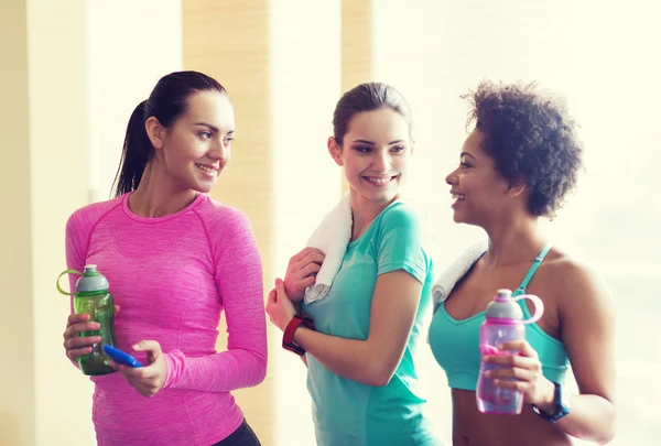 Gelukkig vrouwen met flessen water in de sportschool — Stockfoto