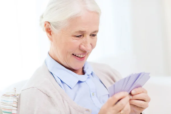 Счастливая пожилая женщина играет в карты дома — стоковое фото