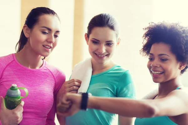 Mulheres felizes mostrando tempo no relógio de pulso no ginásio — Fotografia de Stock