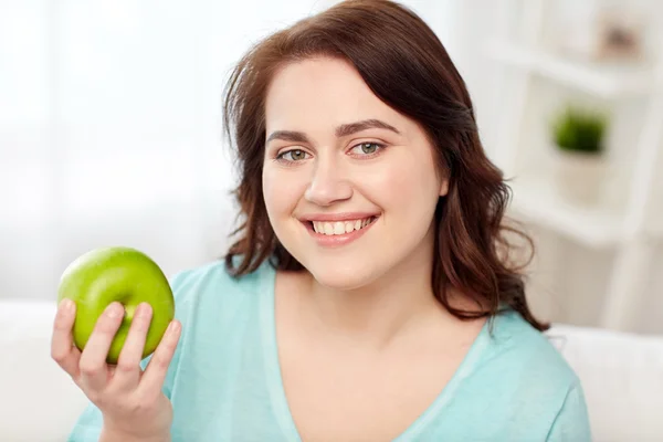 Gelukkig plus grootte vrouw thuis eten van groene appel — Stockfoto