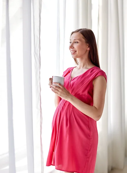 Mujer embarazada feliz con la taza de beber en casa — Foto de Stock