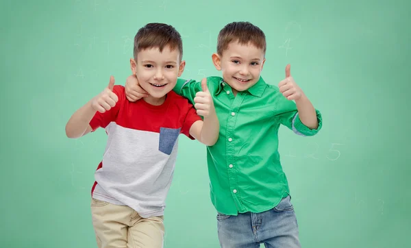 Meninos felizes mostrando polegares para cima sobre placa da escola — Fotografia de Stock