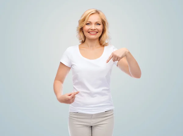 Улыбающаяся женщина в белой футболке, указывающая на себя — стоковое фото