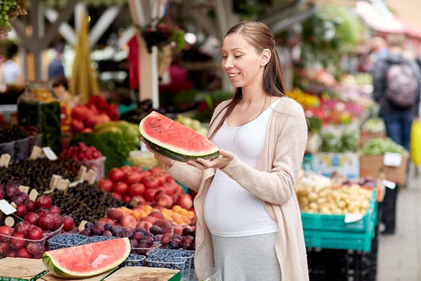 Mujer embarazada sosteniendo sandía en el mercado callejero — Foto de Stock