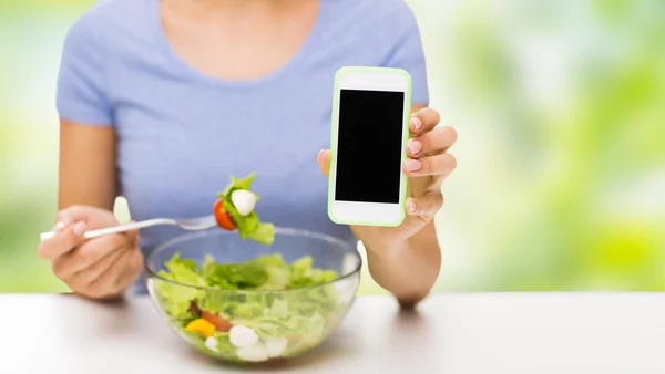 Närbild på kvinna med smartphone äta sallad — Stockfoto